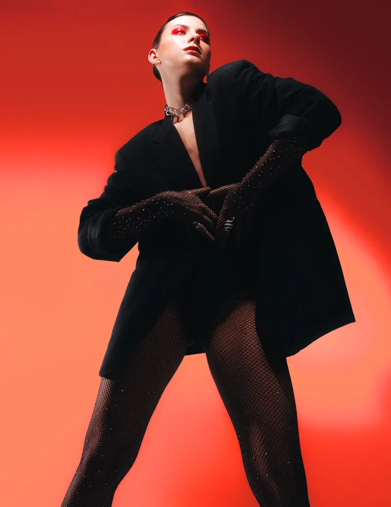 Model in an oversized black blazer against a red backdrop