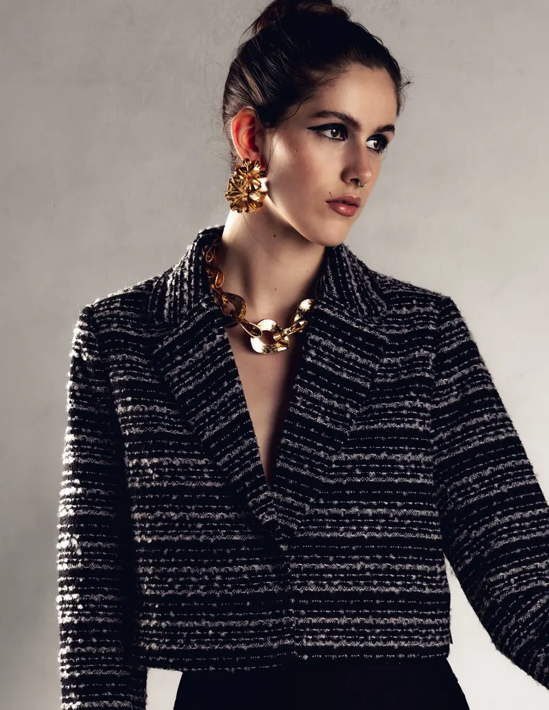 Model in a tweed jacket with a gold statement necklace